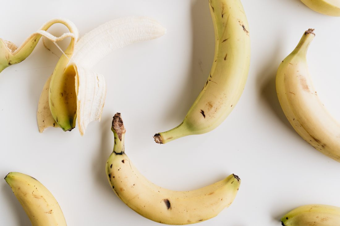 Raw yellow bananas, including one partly peeled banana